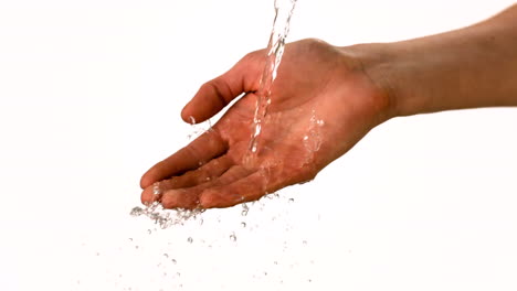 agua derramando sobre la mano de la mujer