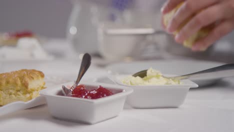 close up shot of person with traditional british afternoon tea with scones cream and jam 5