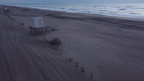 vuelo aéreo alrededor del puesto de vida en la playa durante el amanecer en la mañana y las tranquilas olas del océano como telón de fondo