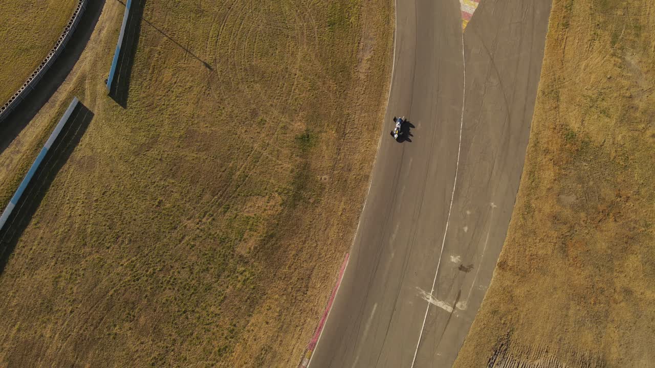 una toma aérea de inclinación dinámica mientras rastrea un auto de carreras que pasa por debajo del dron