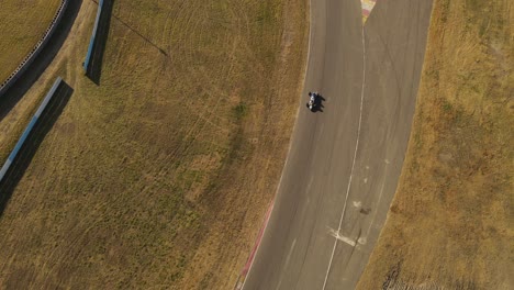 a dynamic tilting aerial shot while tracking a running race car passing below the drone