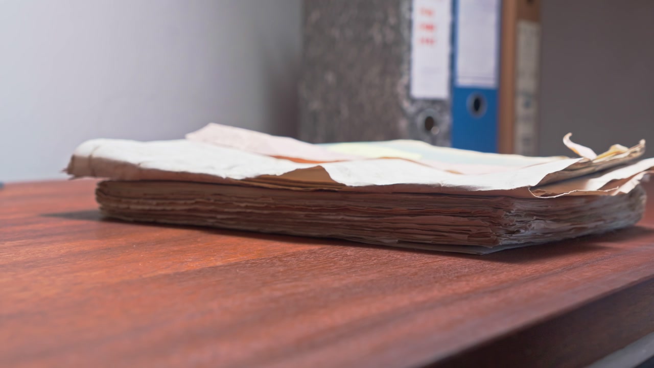 Administrator piles old paper archive documents onto office desktop