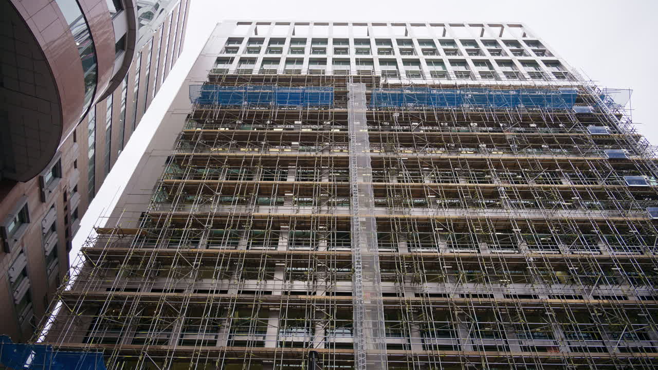 Close-up of a building facade covered in scaffolding and protective mesh during construction or renovation. London, England