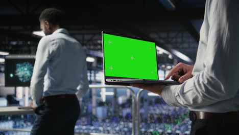 close up of server room worker using green screen laptop next to colleague