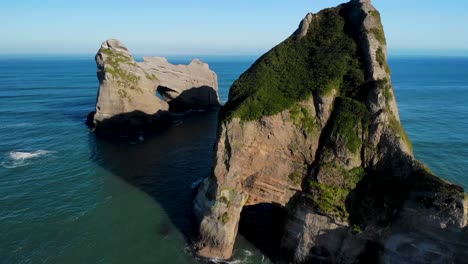 Aerial-fly-over-stunning-rock-formations-at-Wharariki-Beach