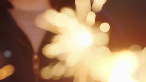 close up sparklers happy woman celebrating independence day enjoying new years eve celebration having fun with festive fireworks on beach at sunset