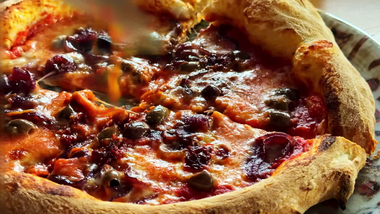 Ripresa ravvicinata di una pizza fresca tagliata con coltello e forchetta a un tavolo di ristorante. Formaggio fuso, salsa di pomodoro e una crosta croccante esaltano la classica esperienza della pizza.