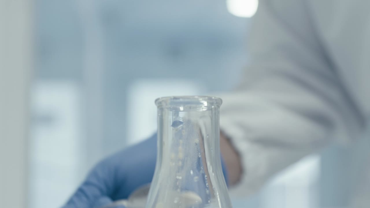Worker's hand pouring serum powder into Measuring Tube while working in Medical Drug Production