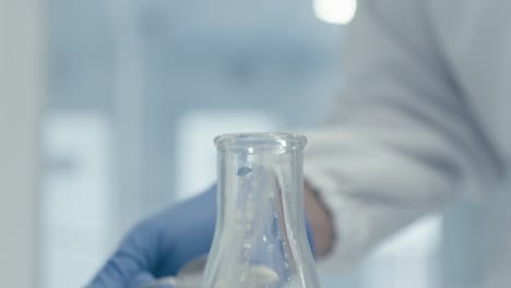 worker's hand pouring serum powder into measuring tube while working in medical drug production