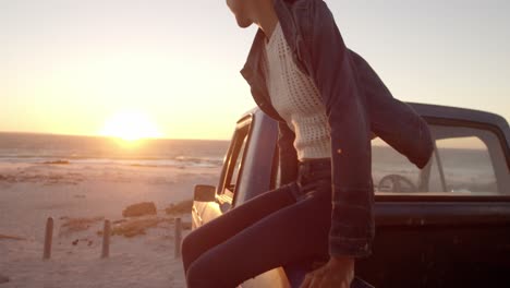 Woman-sitting-on-trunk-of-pickup-truck-at-beach-4k