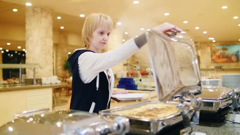 mujer pone verduras en los platos de la cafetería con autoservicio