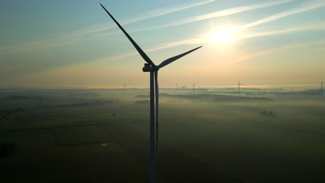 Silhouette-of-a-slowly-rotating-wind-turbine-propeller-over-a-morning-landscape-shrouded-in-fog