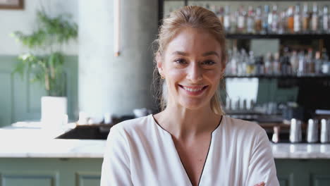 portrait of confident female owner of restaurant bar standing inside by counter