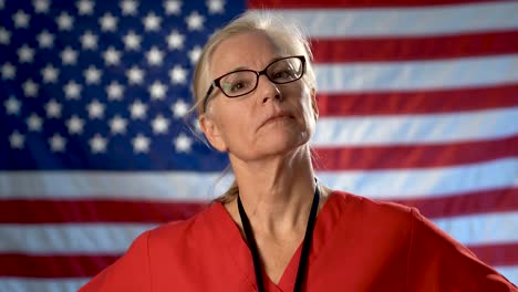 portrait of a nurse showing a seriousness and disapproval set against an out of focus us flag