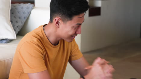 young man in yellow shirt smiling while using laptop at home