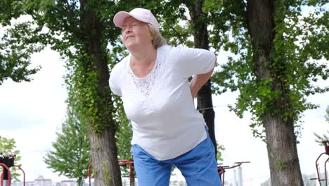 elderly grandmother with low back pain during a morning workout in the park elderly grandmother with low back pain during a morning workout in the park health problems in elderly retirees
