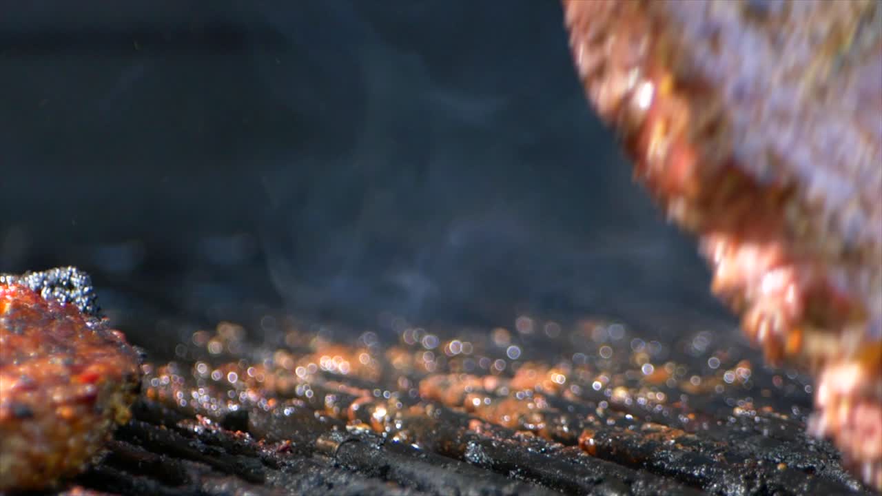 한 쌍의 고기 집게는 그릴에서 거의 익힌 육즙이 많은 립아이 스테이크를 돌립니다.