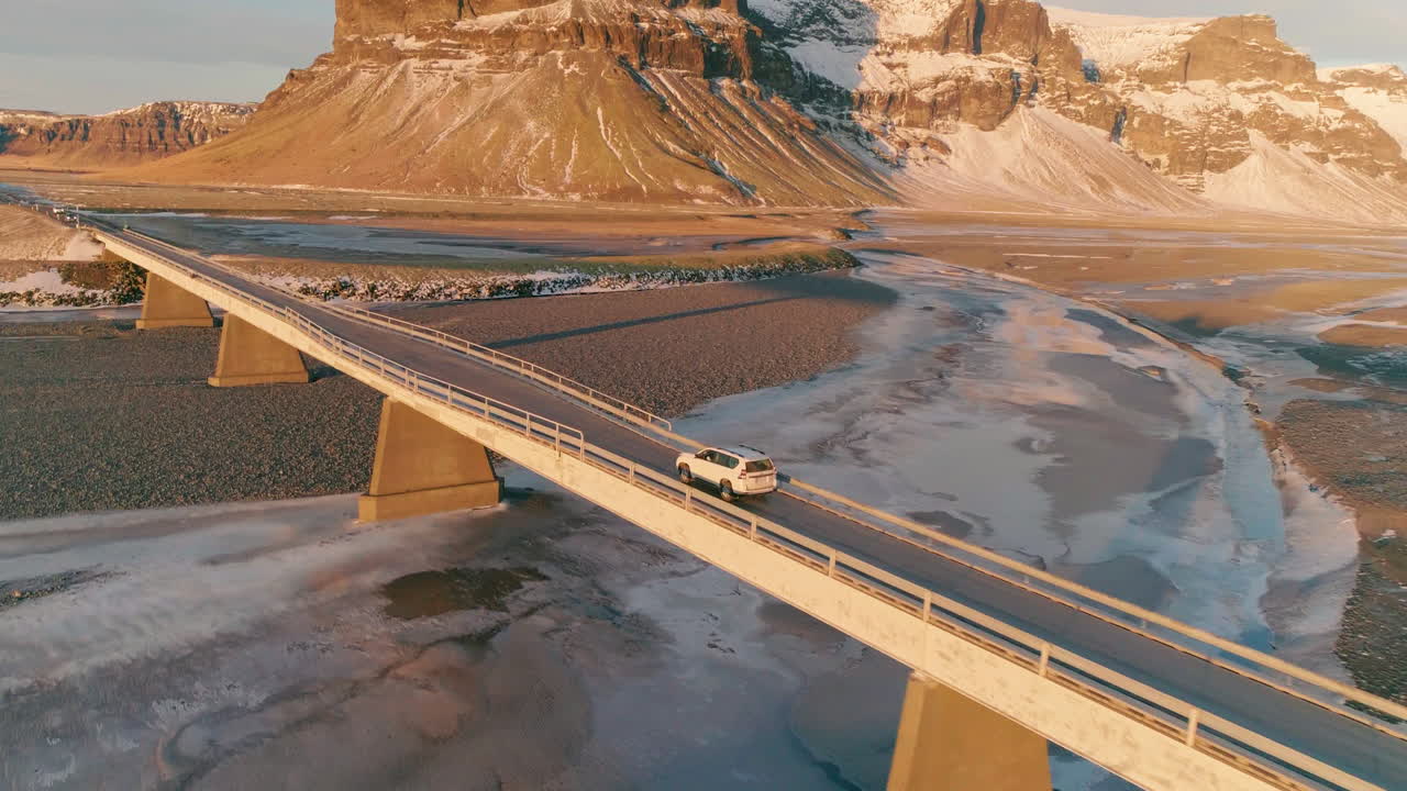 reynisfjara 주요 도로를 가로질러 검은 모래 해변을 가로질러 햇빛이 비치는 산을 향해 이동하는 차량, 공중 궤도를 도는 전망