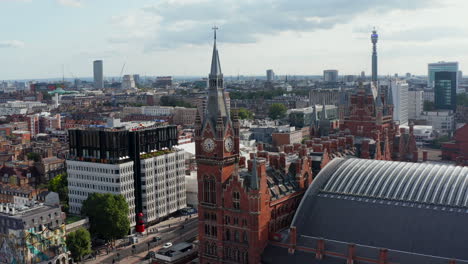 Aerial-footage-of-urban-district.-Nice-old-brick-building-with-decorated-clock-tower.-St-Pancras-train-station-and-hotel.-London,-UK