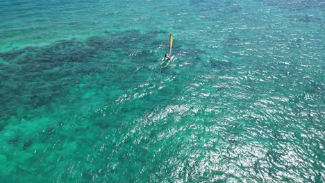 aerial shot of a sailboat in crystal clear waters near the coast of bayahibe at the dominican republic