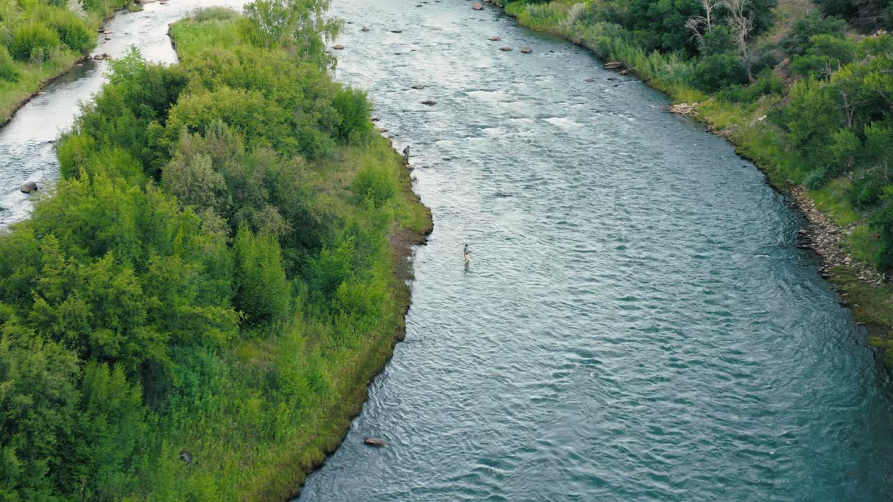 A slow pan across the Animas from above, highlighting color shifts in the water, the flow, and subtle movement in the landscape. Two fisherman cast their fly fishing rods while wading.