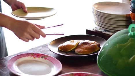 hand serving pancakes onto a plate