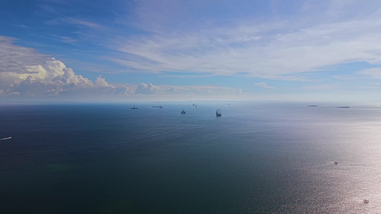 Wide aerial shot of offshore oil rigs near Labuan, Malaysia, surrounded by calm blue ocean and distant clouds. Industrial scene symbolizing energy, exploration, and maritime technology
