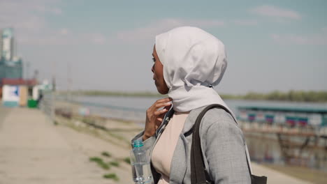 mujer negra molesta ajusta el hijab en la estación de botes del río