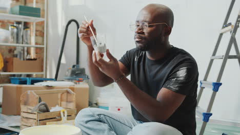 Black Man Mixing Paint and Checking Color during Home Renovation