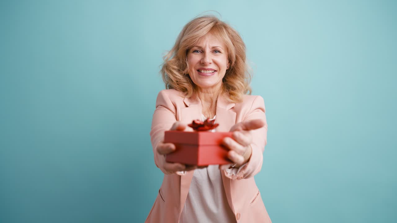 Donna felice presenta una scatola regalo rossa alla telecamera