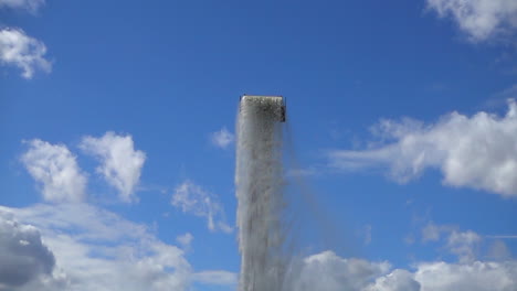 Slow-motion-shot-of-a-tall-water-fountain-with-blue-sky-in-the-background
