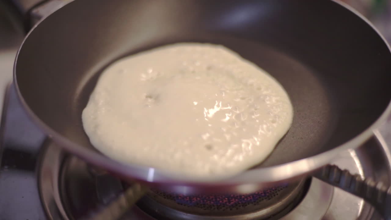 Fluffy pancake cooking on heat stove pan closeup