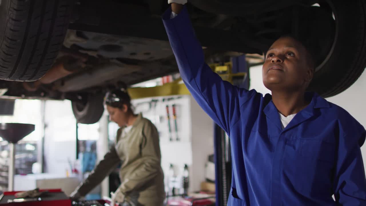 video de una mujer afroamericana mecánica de coches comprobando un coche
