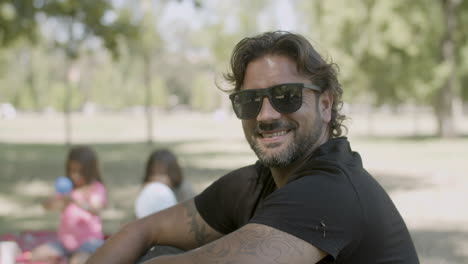 vista frontal de un hombre sonriente arreglando gafas y mirando a la cámara