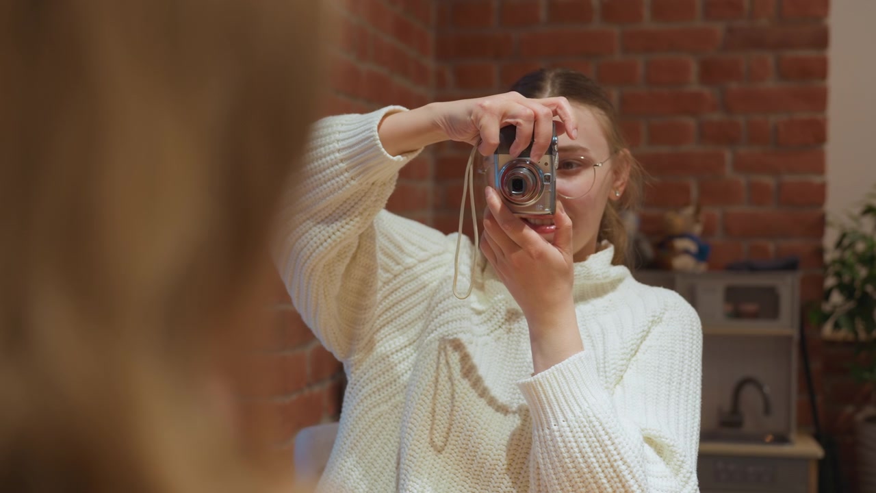 Giovane donna che scatta una foto con una fotocamera digitale in interni