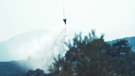 helicóptero que volaba hacia un incendio forestal que arrojaba agua