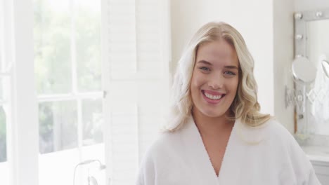 Portrait-of-happy-caucasian-plus-size-woman-wearing-bathrobe-in-bathroom-in-slow-motion