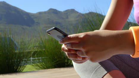 Mid-section-of-young-woman-using-mobile-phone-on-a-sunny-day-in-backyard-of-home-4k