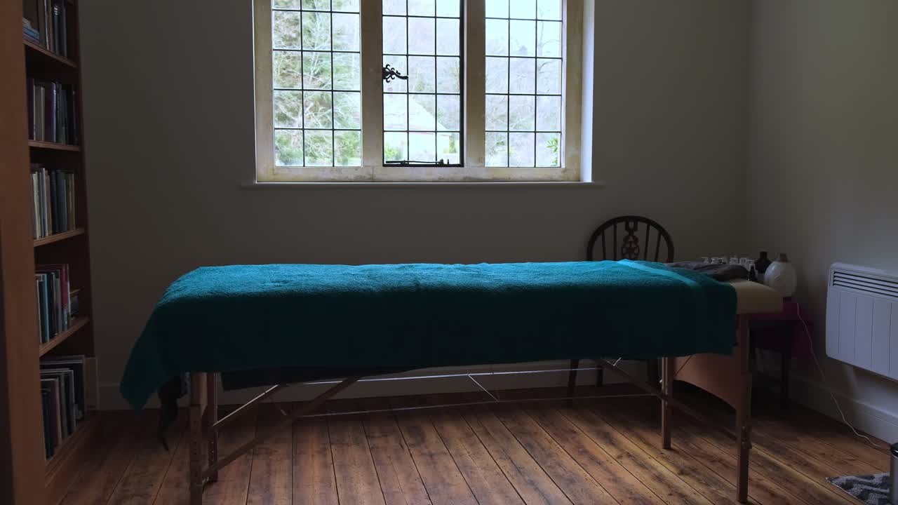Cinematic wide shot of empty relaxing quit massage room with towels, oils and massage table.
