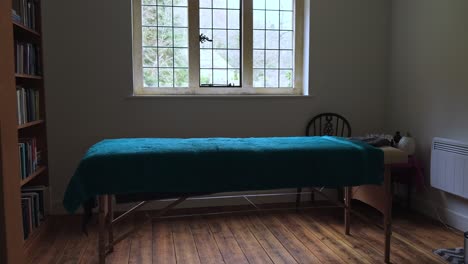 cinematic wide shot of empty relaxing quit massage room with towels, oils and massage table.