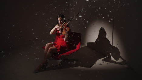 woman playing violin in red dress under snow