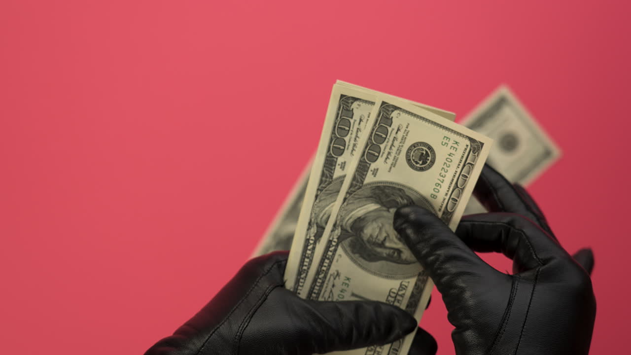 Gloved Hands Counting and Dropping Hundred Dollar Bills on Pink Background