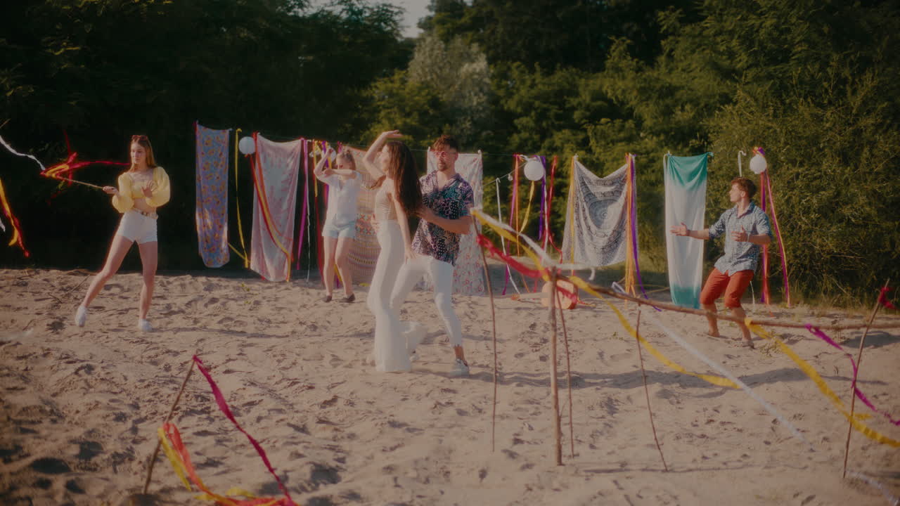 молодая женщина и мужчина танцуют бачату с друзьями на пляже.