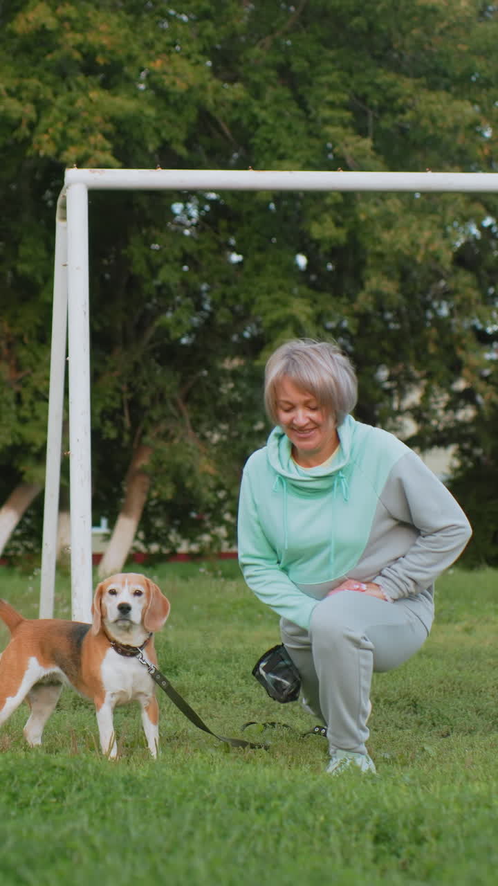 햇살 좋은 공원에서 민트색 후드티와 회색 트레이닝복을 입고 비글 강아지와 함께 즐겁게 뛰어노는 백인 할머니, 활기찬 훈련 시간, 비글은 깡충거리며 냄새를 맡고, 할머니는 웃으며 걷는 모습, 행복한 유대감