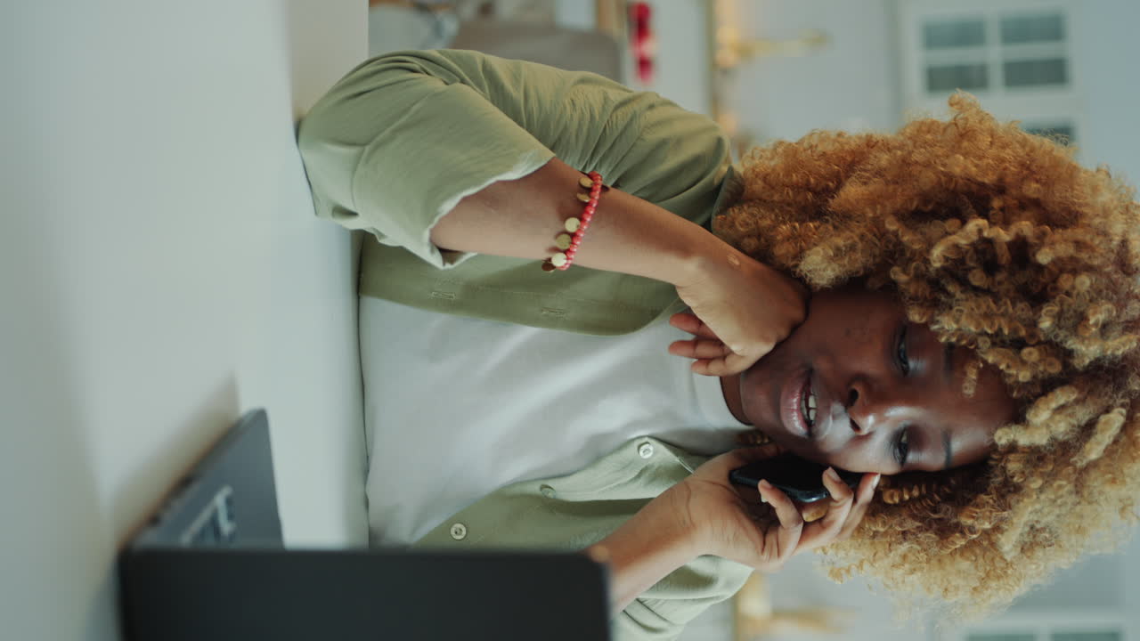 Black Woman Having Phone Talk and Working on Laptop at Home