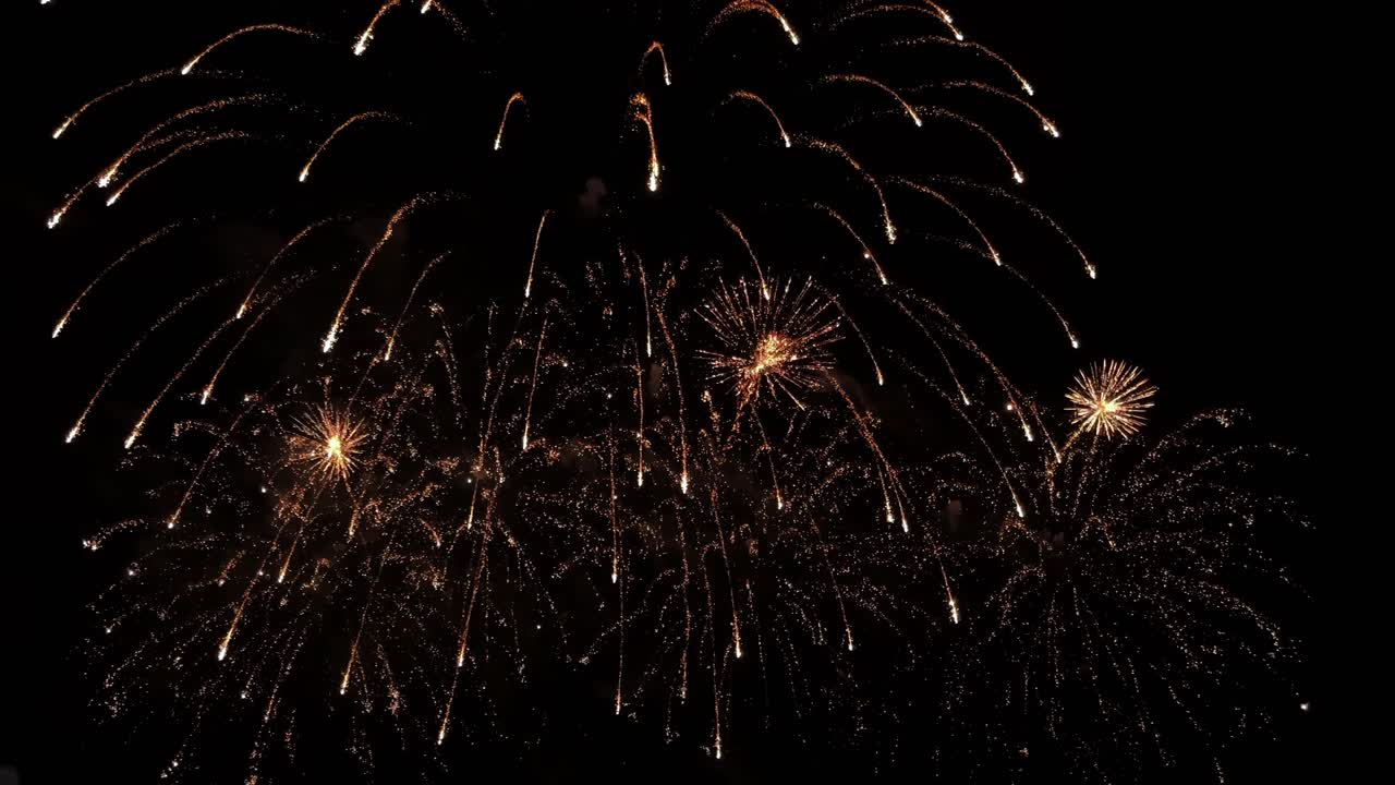 exhibición pirotécnica estallando en el aire una tras otra, y cayendo hacia atrás a medida que sus luces se desvanecen
