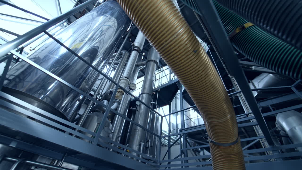 Innovative technological equipment for milk products manufacturing. Steel tubes and tanks at the dairy enterprise. Circle movement around the plant, view from below.