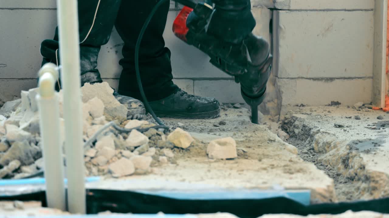 방이나 집에서 건설 및 수리 - 콘크리트 개를 깨뜨리는 전기 도구 - 마스터는 퍼로 콘크리트를 깨뜨립니다.