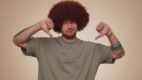 upset man in casual t-shirt showing thumbs down sign gesture, disapproval, dissatisfied dislike