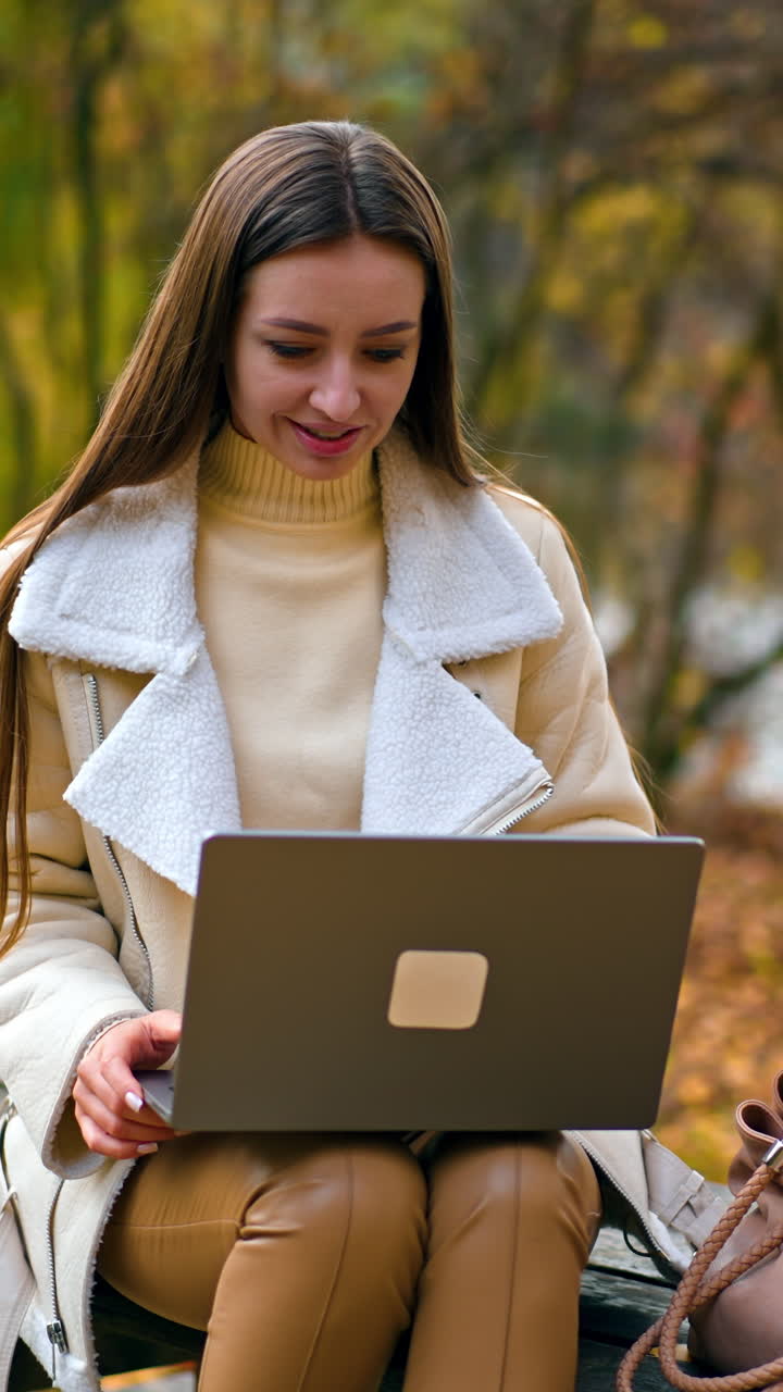 Beautiful lady online studying outdoor in park. Young lady working with laptop. Vertical video